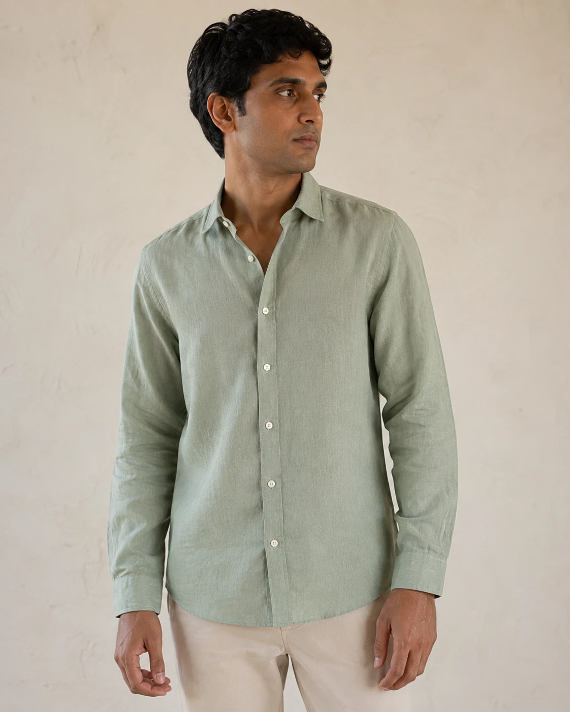AI-generated Indian model wearing a sage-green linen shirt with stone-colored trousers