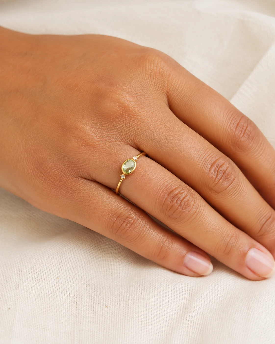 AI-generated close-up of a gold ring with a pale-green stone worn on a hand
