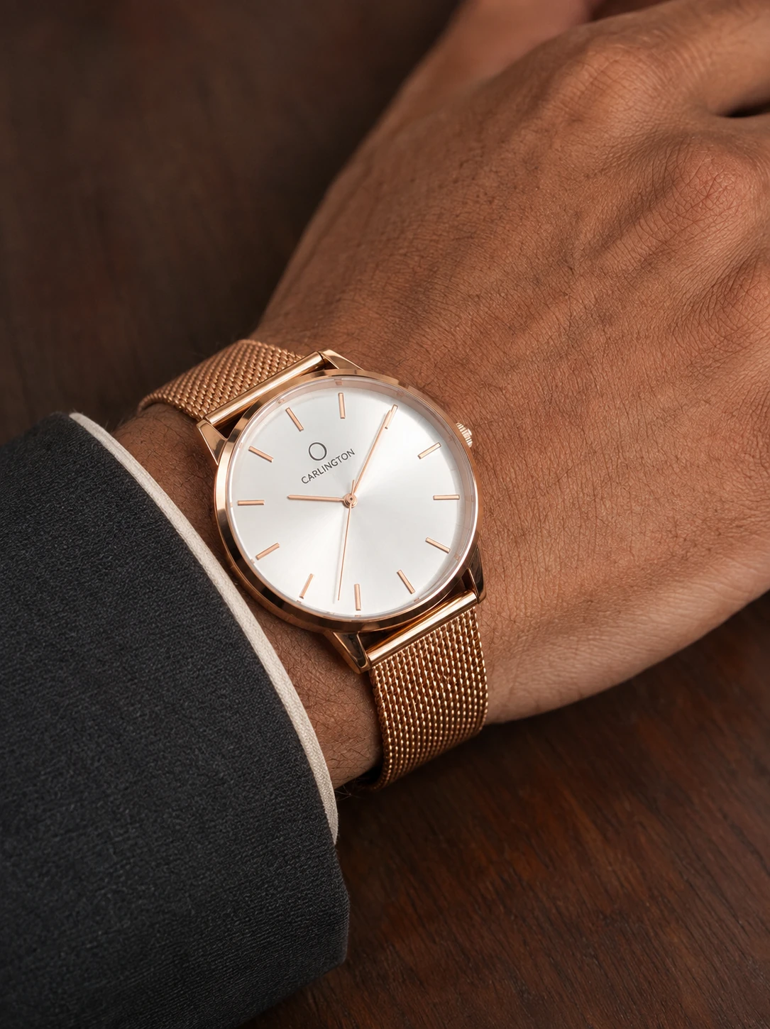 AI-generated close-up of a rose-gold mesh watch styled with a charcoal jacket on a walnut surface
